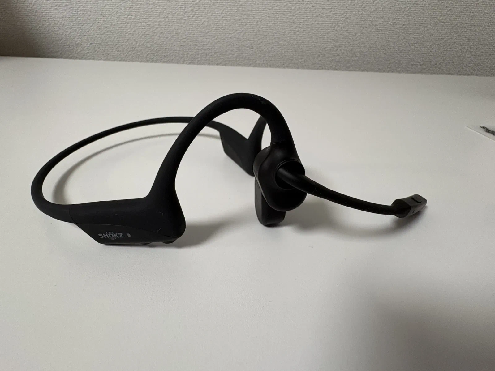 Shokz OpenComm2 の全体。ネックバンドの右側から、口元へブームマイクが伸びている