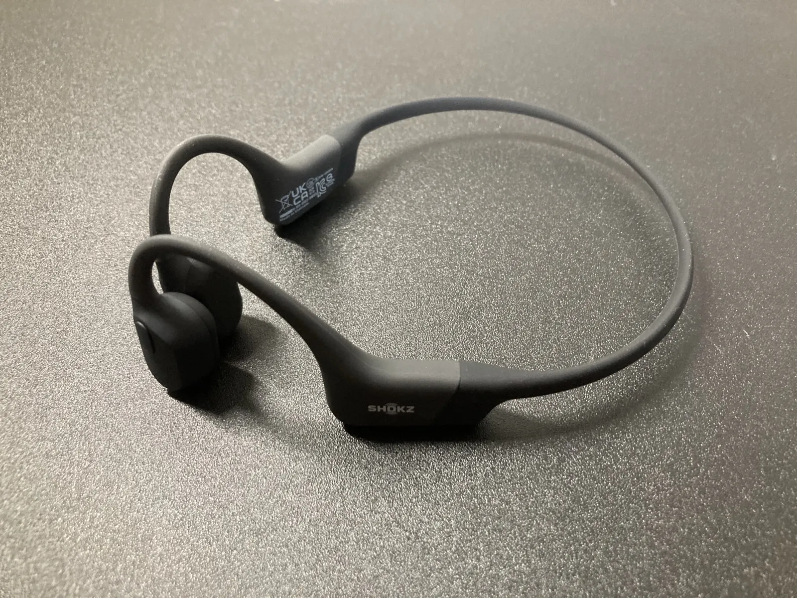 箱から出した Shokz OpenRun 本体。黒いネックバンドとイヤーフック、耳の前に当たるトランスデューサー